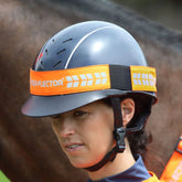 Person wearing a helmet with an orange band and visible brand logo, standing in front of a horse.